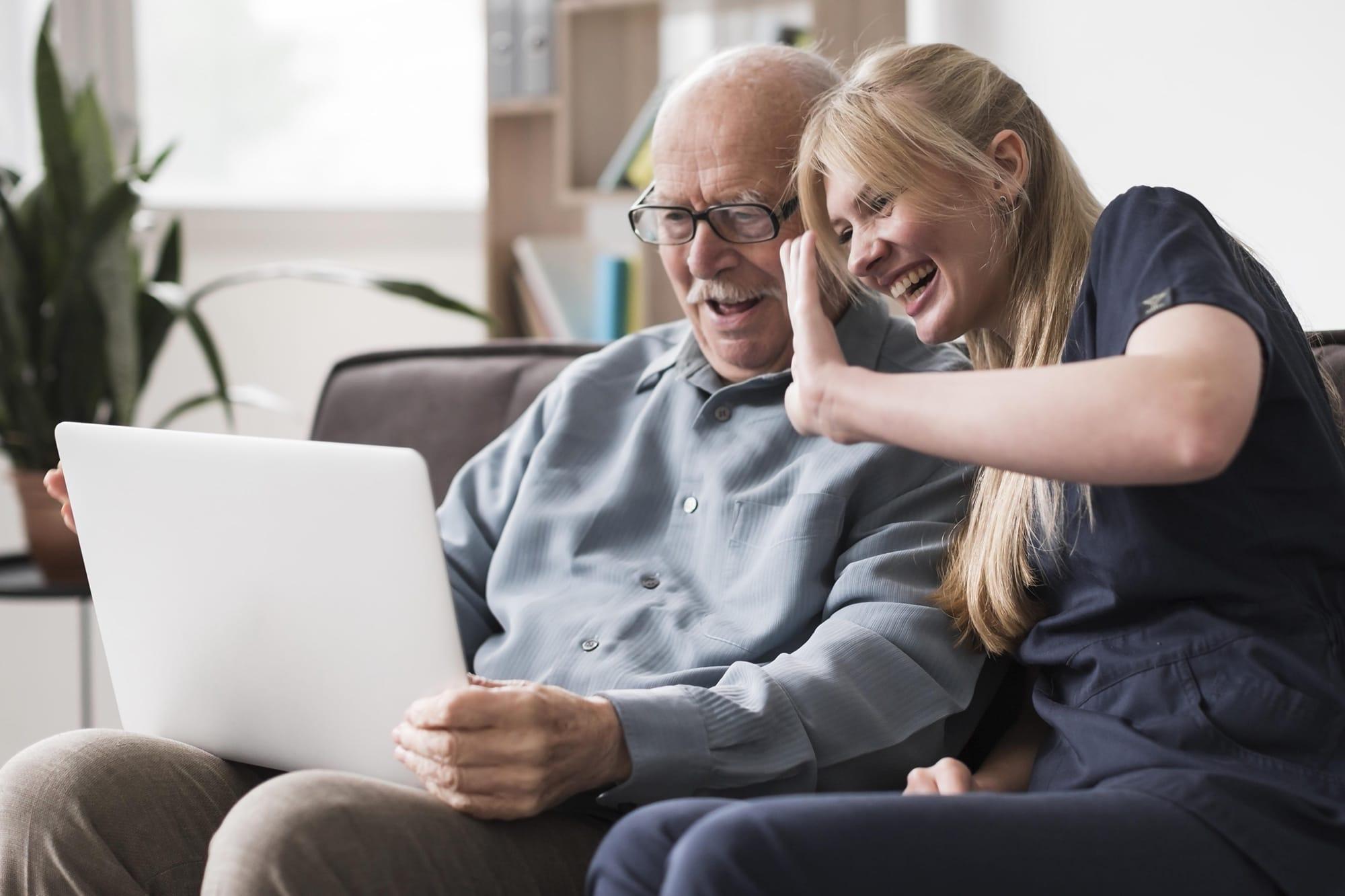 Smiley older man with nurse having video call on laptop